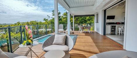 A modern outdoor deck with a pool, seating, and a kitchen area.