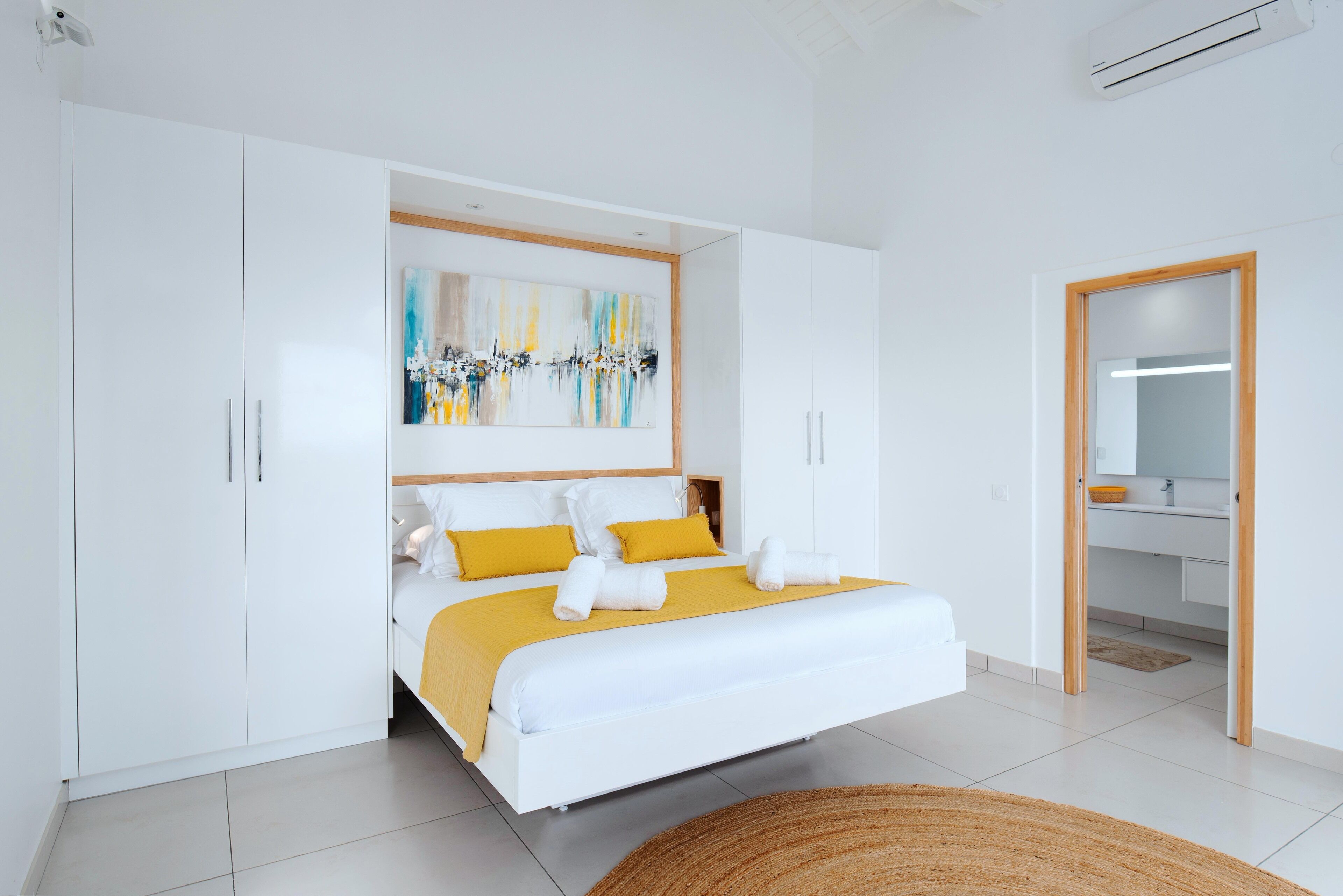Un dormitorio moderno con una cama grande, un armario blanco y un cuadro en la pared.