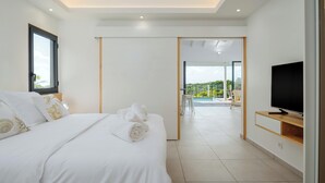A modern bedroom with a bed, a TV, and a view of a balcony. - Vista del Mar (Sainte-Anne)