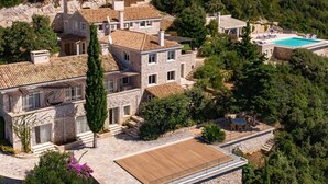 A stone villa with a swimming pool, terraced garden, and a wooden deck.