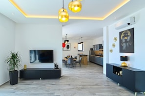 Ein modernes Wohnzimmer mit Flachbildfernseher, Essbereich und Küche.