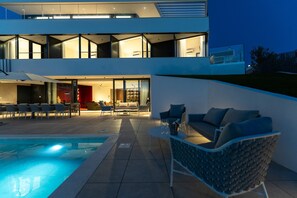 Ein modernes, zweistöckiges Haus mit Pool, Außenbereich und gut beleuchtetem Innenraum.