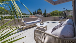 A balcony with wicker furniture, a round table, and a hanging chair.
