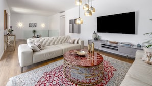A modern living room with a sofa, a coffee table, and a TV mounted on the wall.