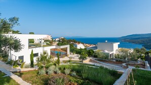 Un quartier résidentiel en bord de mer, avec des immeubles modernes aux façades blanches, une piscine et une vue sur la mer.