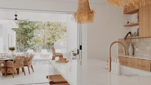 A modern kitchen with a white countertop, wooden cabinets, and a hanging light fixture.