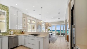 A modern kitchen with white cabinets, a central island, and a view of the ocean.