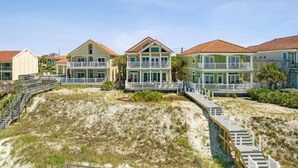 A beachfront property with multiple buildings, a wooden boardwalk, and a sandy beach.