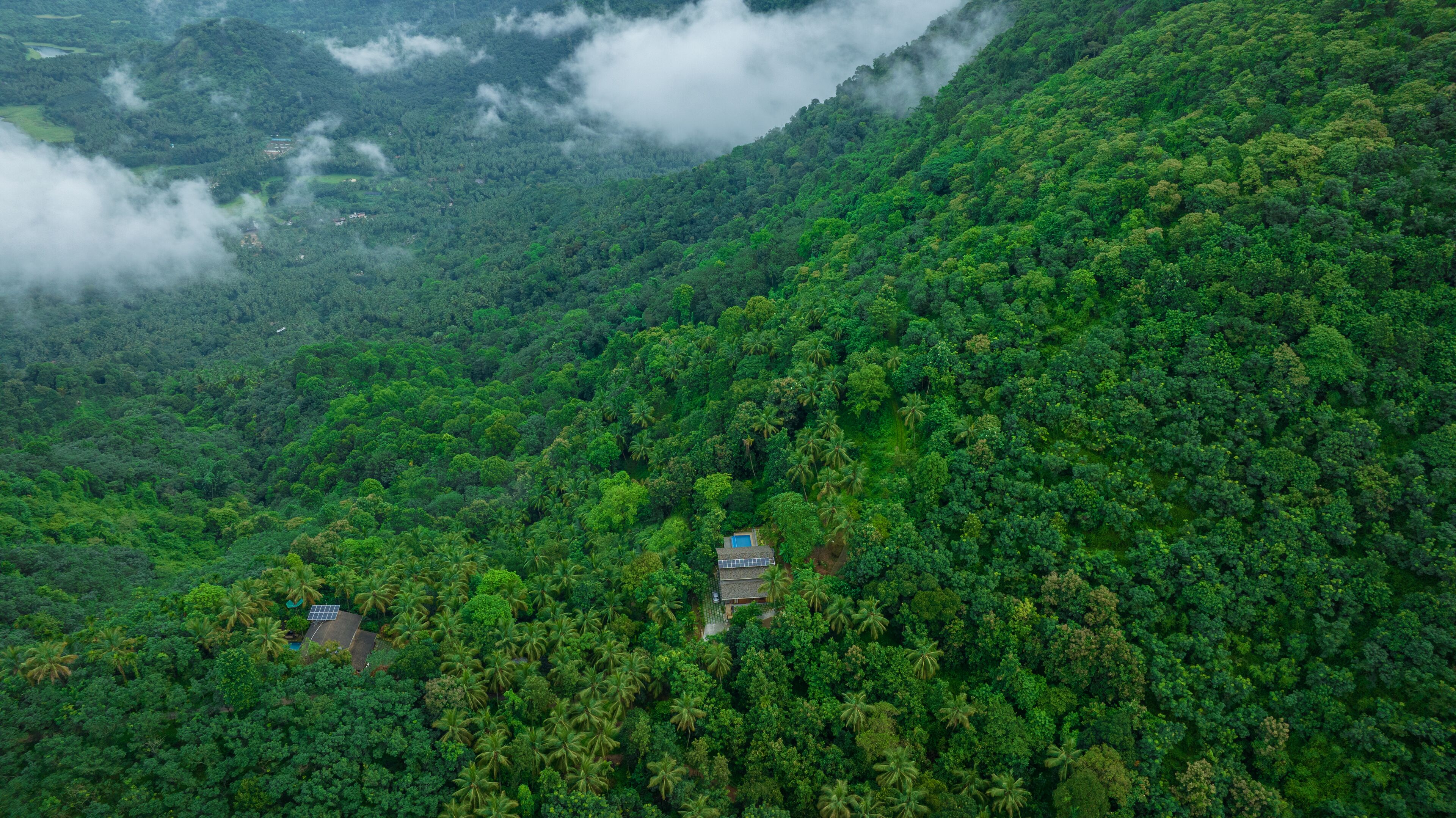 A remote, lush green mountain area with a small building featuring a solar panel roof.
