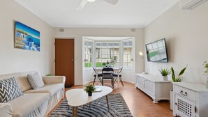 A modern living room with a sofa, coffee table, and dining area. - Vitamin Sea at Henley Beach (Henley Beach)