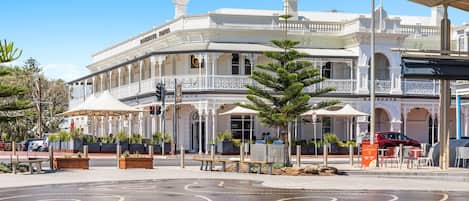 A historic building with a white facade, multiple balconies, and outdoor seating areas.