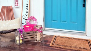 A turquoise door with a heart decoration, a welcome sign, and a 'XOXO' sign.