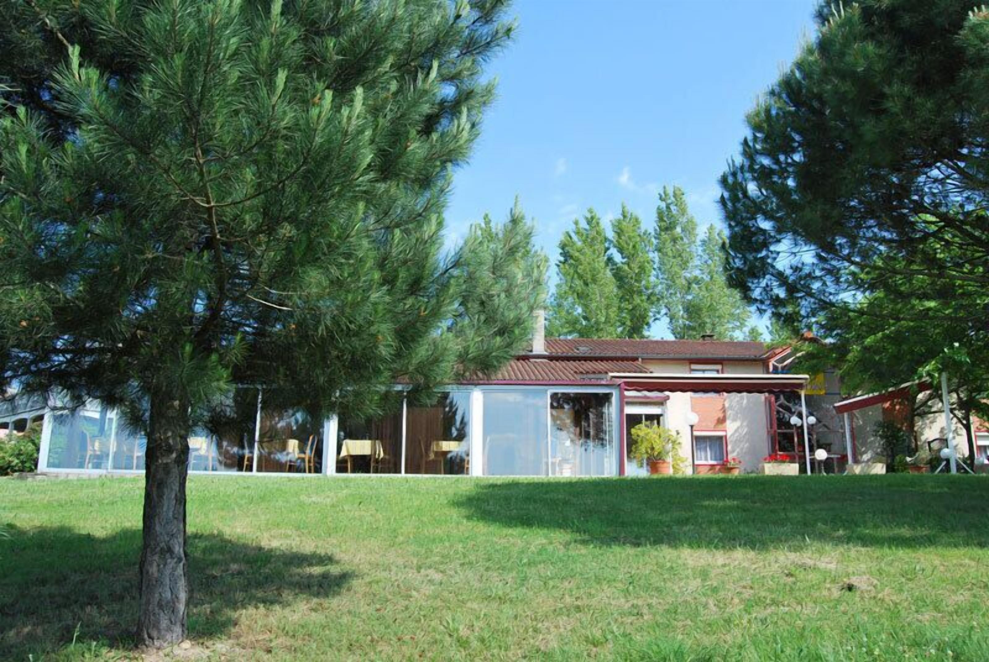 A house with a fenced backyard, a large tree, and a clear sky.