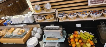 Un bufé de desayuno con diversas opciones de comida, como pan, bollería y frutas.