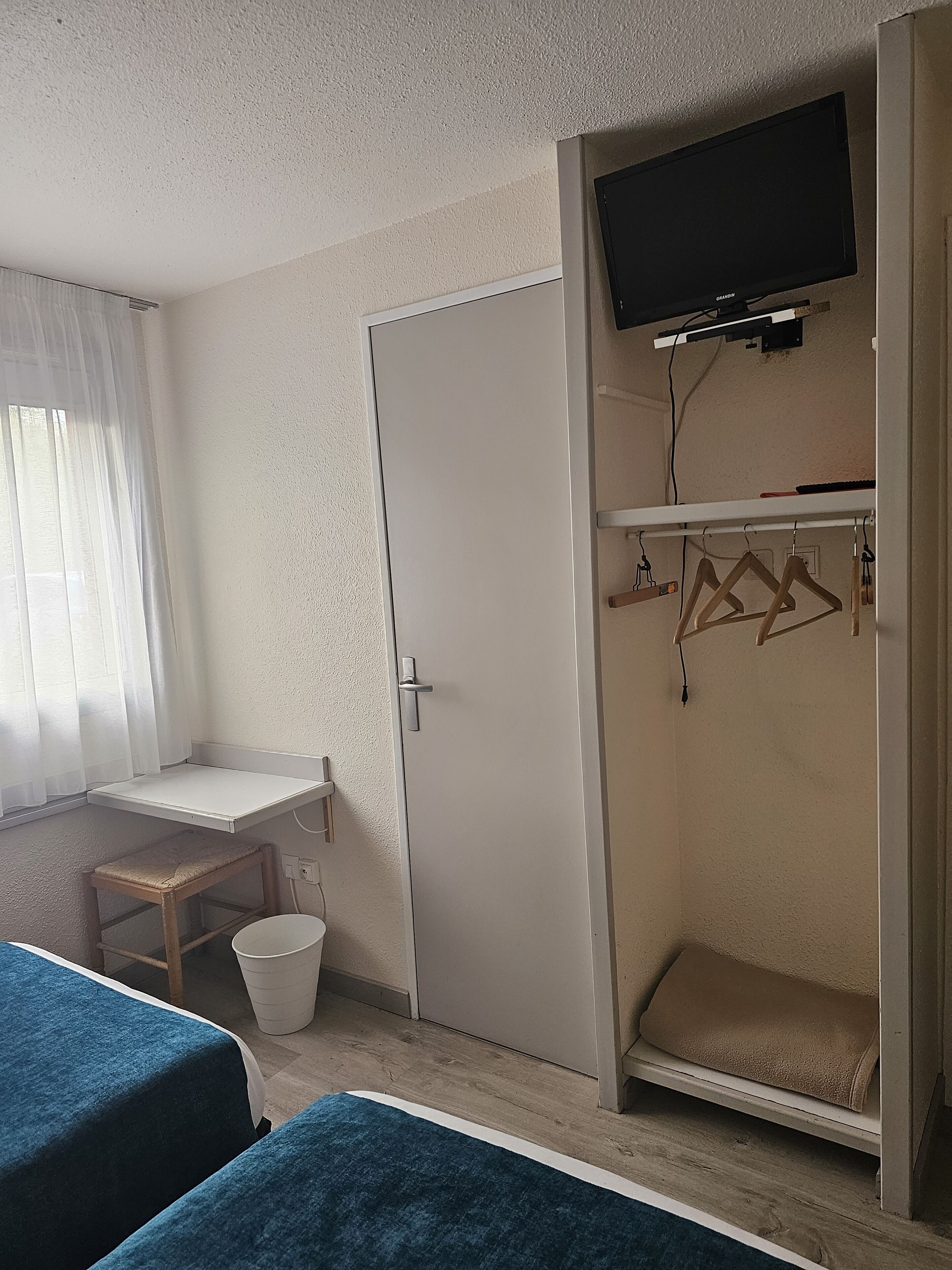 Un dormitorio con dos camas, un escritorio, un televisor y un armario.