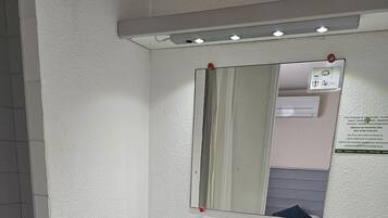 Een badkamer met een wit wastafelmeubel, spiegel en handdoekhouder.