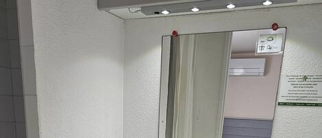 Ein Badezimmer mit weißem Waschbecken, Spiegel und Handtuchhalter.
