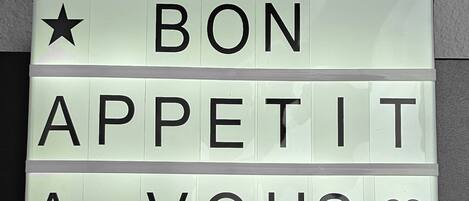 A light-up sign with the message "BON APPETIT A VOUS" and decorative symbols.