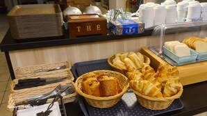 Un bufé de desayuno con pan, pastelería y una estación de café.