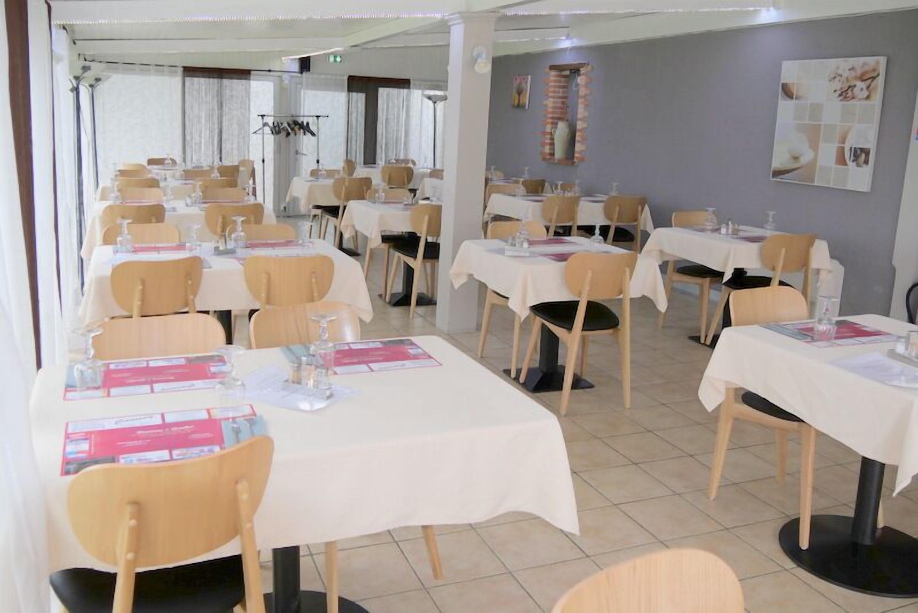 Un restaurante con varias mesas, cada una con sillas, menús y vasos de agua.