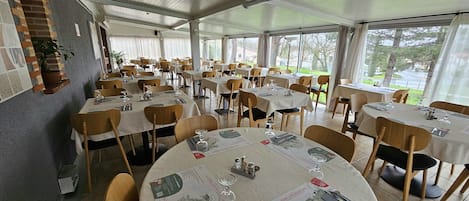 Un ristorante con diversi tavoli apparecchiati per la cena, con menu e bicchieri da vino.