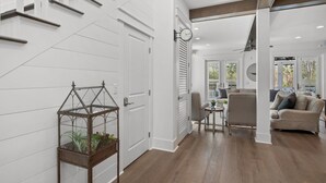 A modern interior with a staircase, a glass terrarium, a clock, and a living area with a sofa and a coffee table. - 6 Bikes & New 6-Seater Golf Cart, Blue Heron Haven Private Heated Pool! (Santa Rosa Beach)
