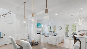 A modern kitchen with white cabinetry, a central island, and pendant lighting. - Beaches Be Crazy FREE 6-Seater Golf Cart and 6 Bikes 2 Pools, Pickleball Courts at NatureWalk 30A! (Santa Rosa Beach)