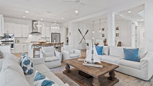 A spacious living room with a white sofa, a wooden coffee table, and a dining area with a wooden table and chairs. - Beaches Be Crazy FREE 6-Seater Golf Cart and 6 Bikes 2 Pools, Pickleball Courts at NatureWalk 30A! (Santa Rosa Beach)