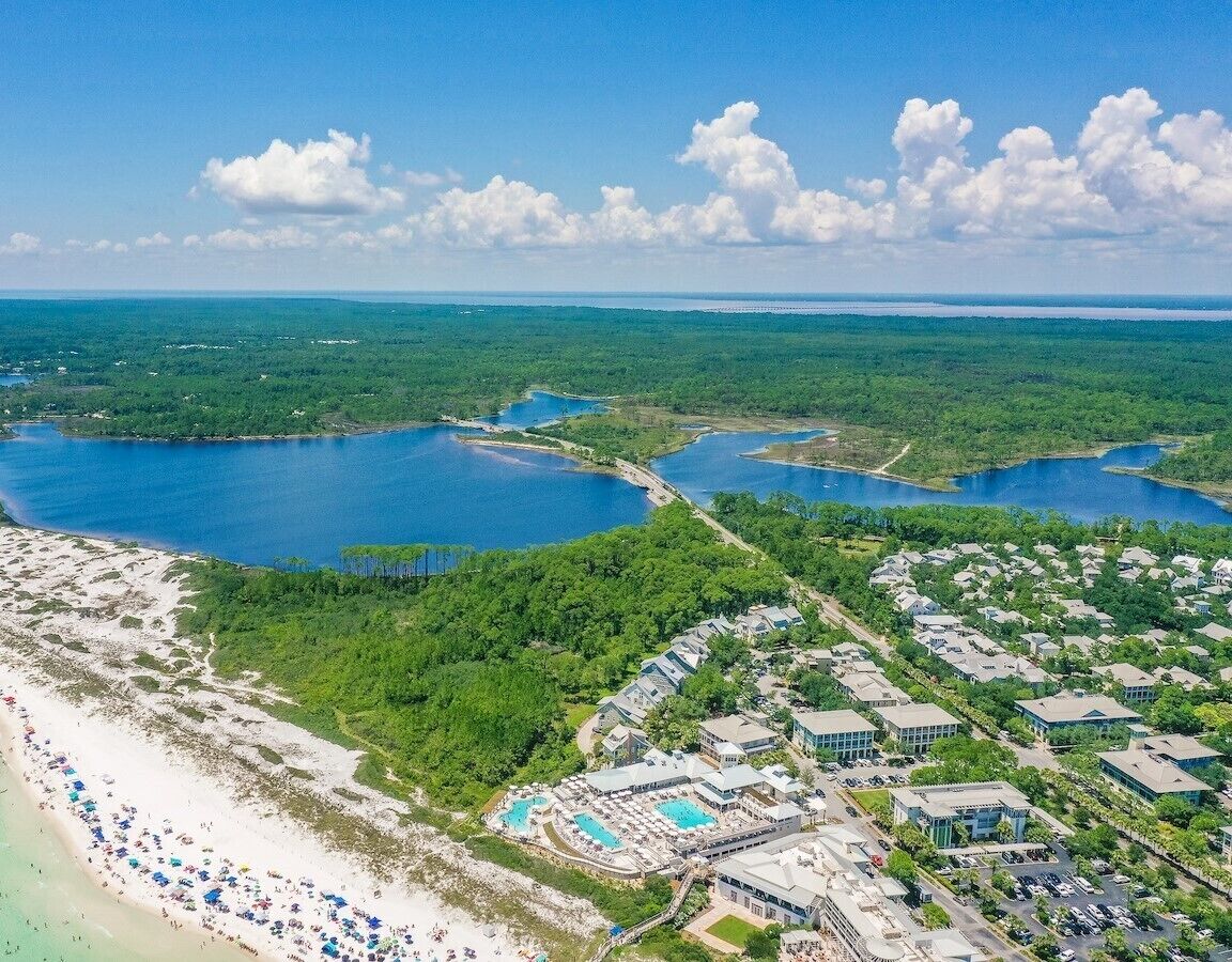 Une vue aérienne d’une station balnéaire comprenant plusieurs bâtiments, une plage et une vaste étendue d’eau.