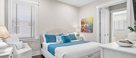A bedroom with a bed, a chair, a nightstand, a ceiling fan, a window with blinds, and a door.