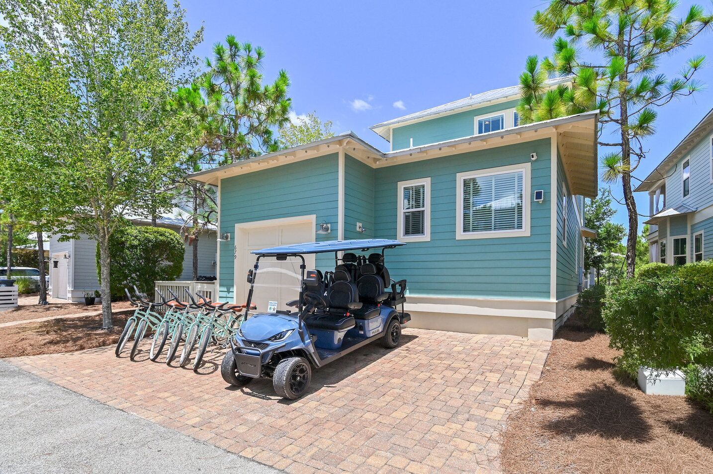 A residential building with a garage, a golf cart, and bicycles parked outside.