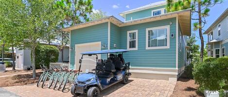 A residential building with a garage, a golf cart, and bicycles parked outside.
