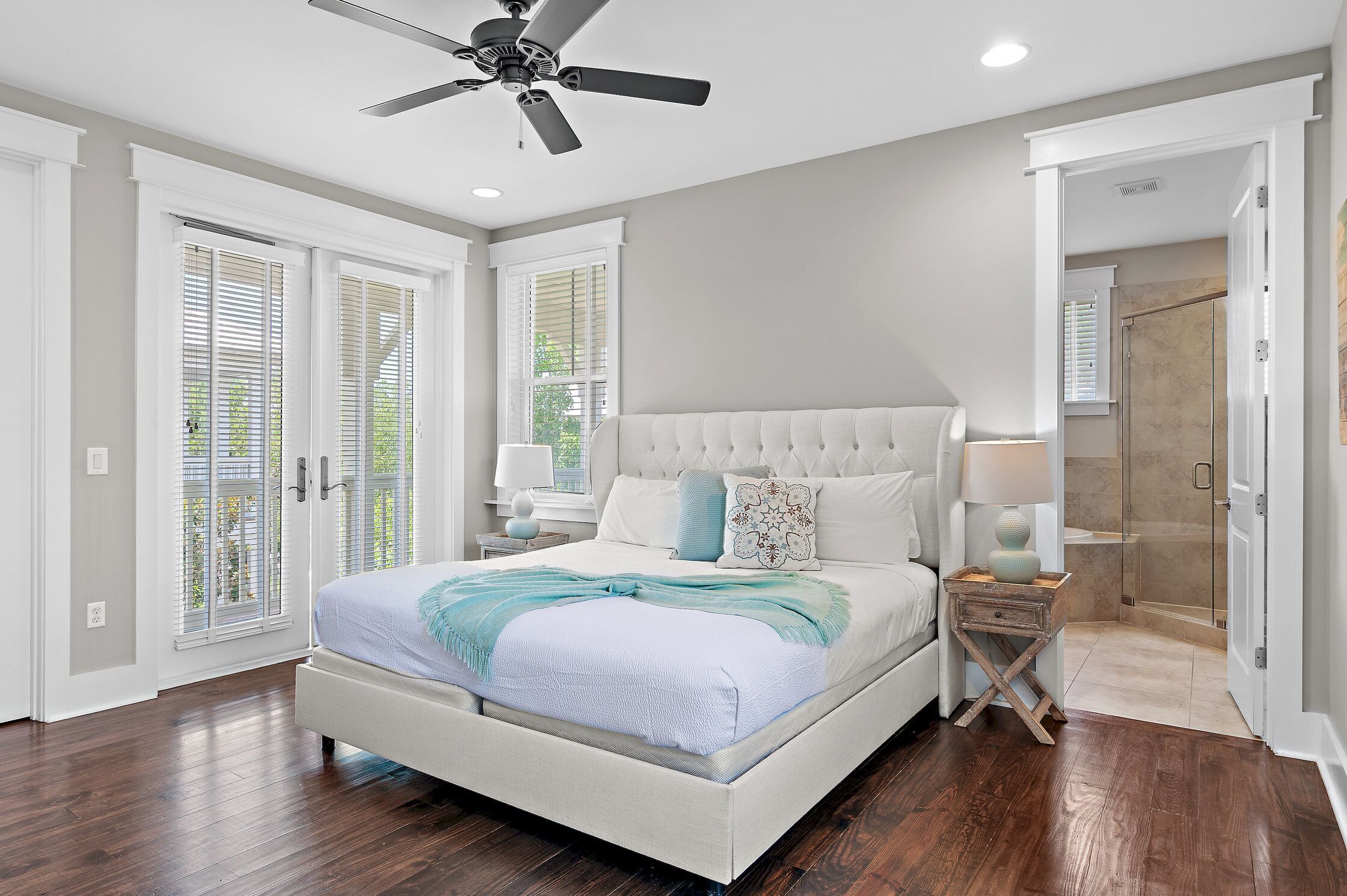 A bedroom with a large bed, a ceiling fan, a nightstand, and a walk-in closet.