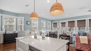 Una cocina amplia con una isla grande, luces colgantes y un comedor con sofá y sillas.