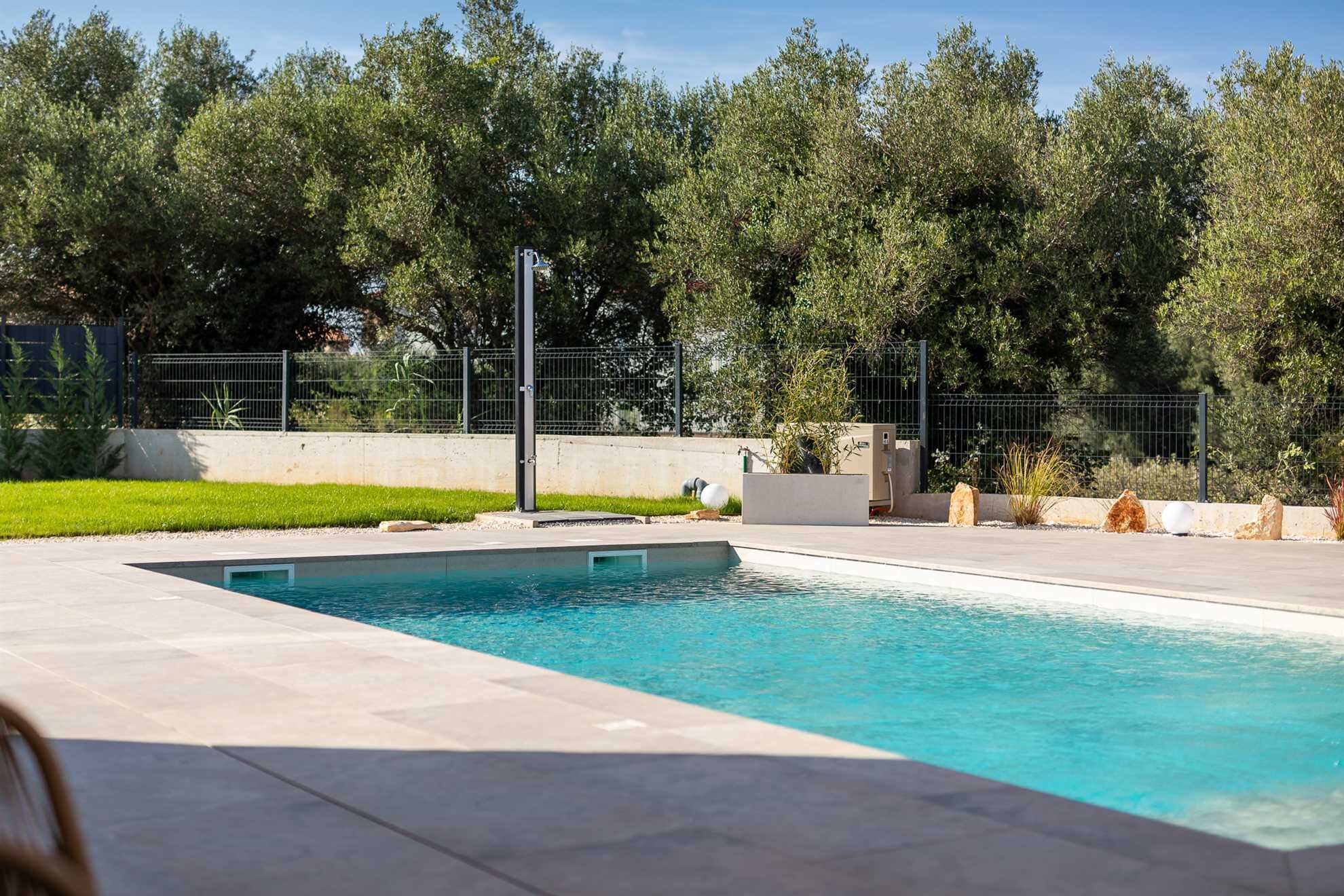 Una piscina rectangular amb superfície d'aigua blava i translúcida, envoltada per un sòl de formigó.