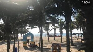 A beach scene with palm trees, a small hut, and a large arch structure.