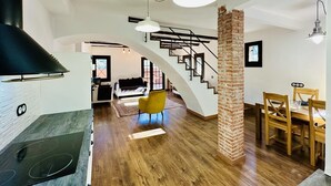 A spacious living area with a kitchen, dining table, and a staircase leading to another level.