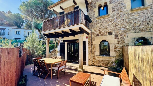 A stone building with a balcony, outdoor seating, and a view of the surrounding area.