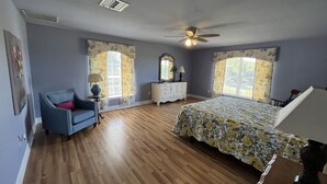 A bedroom with a bed, a dresser, a chair, and two windows with curtains. - Lakefront Guesthouse on 230 Acres - Very Private - Connect with Nature in style! (Umatilla)