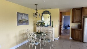 A dining area with a round table and chairs, a chandelier, a mirror, and a painting on the wall. - Lakefront Guesthouse on 230 Acres - Very Private - Connect with Nature in style! (Umatilla)