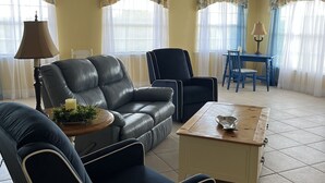 A living room with a sofa, chairs, a coffee table, a lamp, and a ceiling fan. - Lakefront Guesthouse on 230 Acres - Very Private - Connect with Nature in style! (Umatilla)