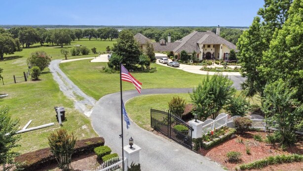 A residential area with a large house, a flag, and a well-maintained lawn. - Lakefront Guesthouse on 230 Acres - Very Private - Connect with Nature in style! (Umatilla)