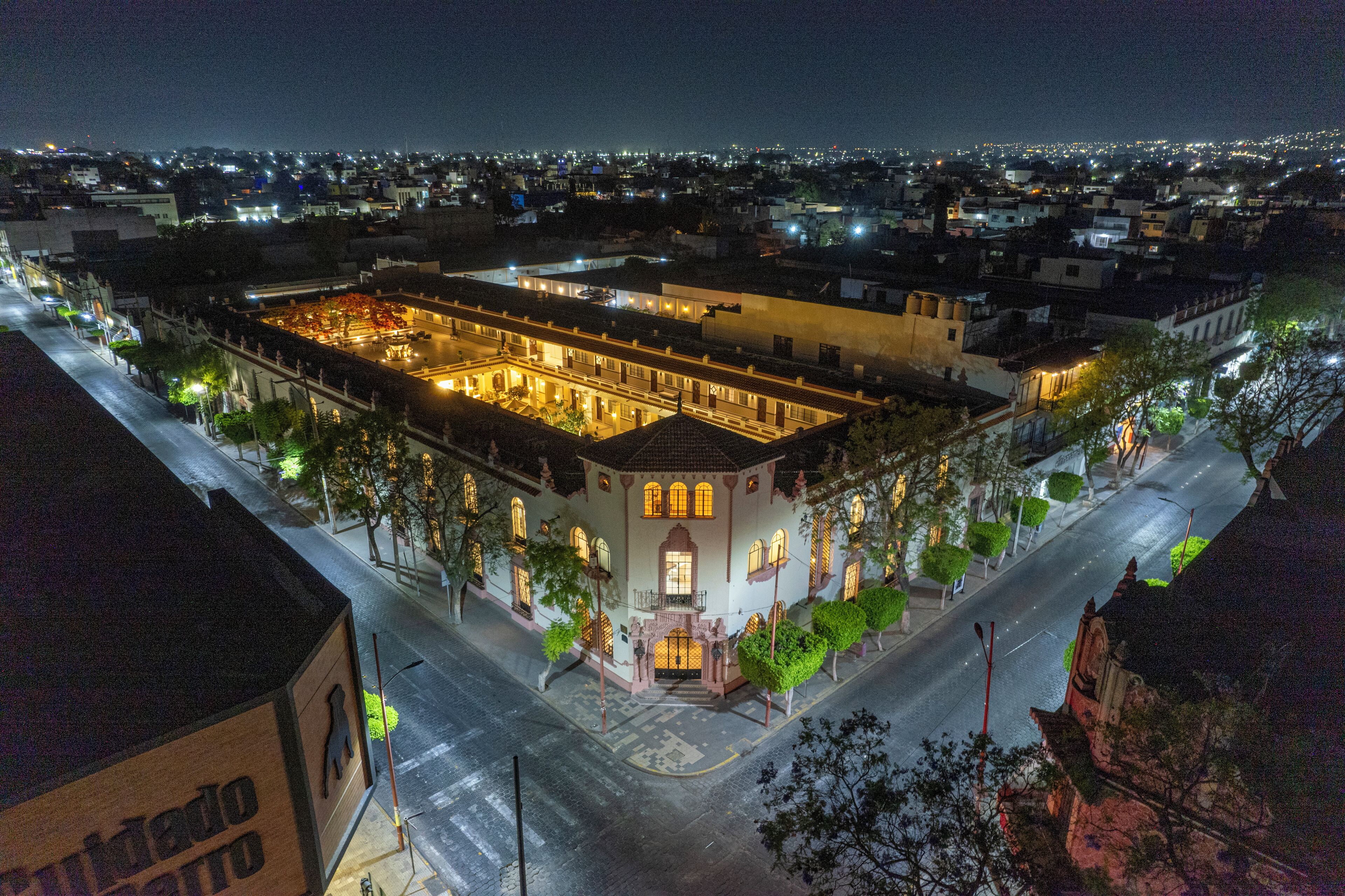 A historic building with a central courtyard, surrounded by trees and a street.