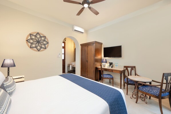 Habitación de hotel con cama, escritorio, sillas y televisor.