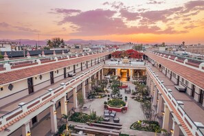 Un patio de hotel con varios niveles, mobiliario exterior y un jardín central.