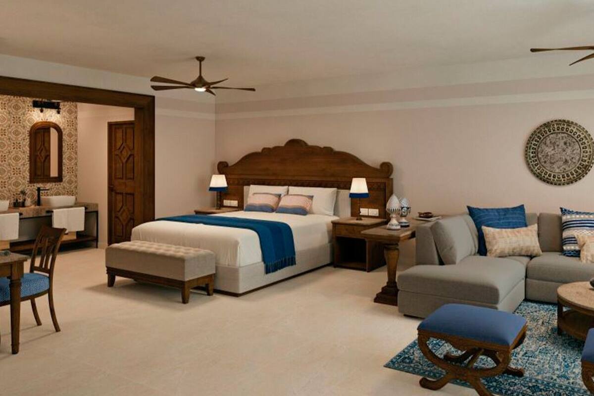 A bedroom with a large bed, bedside tables, a sofa, a chair, and a desk.