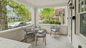 Une véranda avec quatre fauteuils en osier, une table en béton et un mur en briques.
