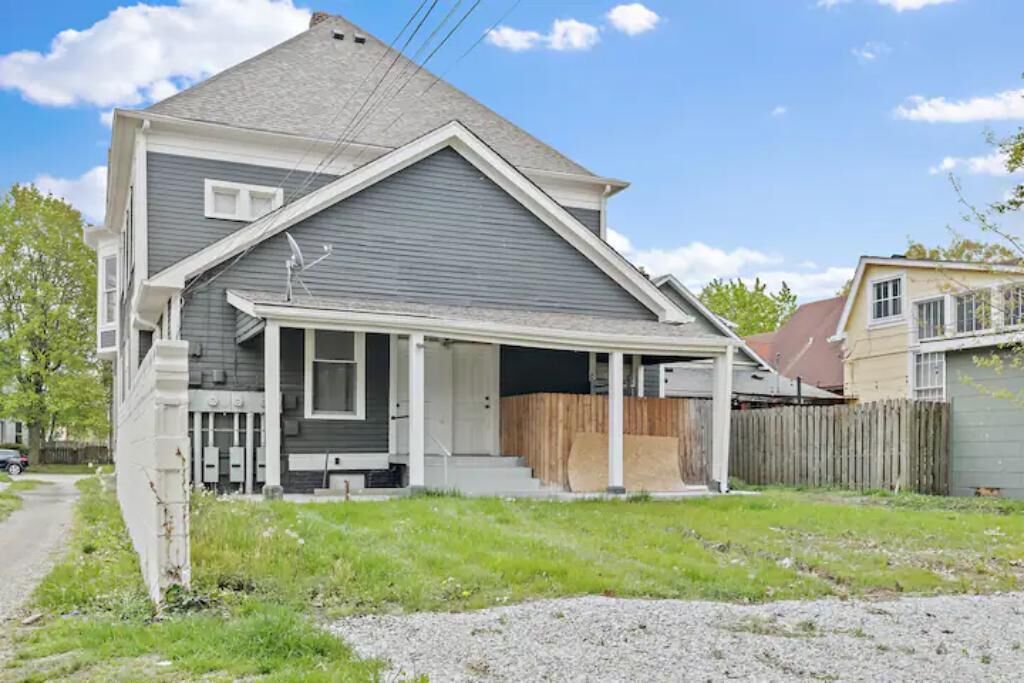 A two-story house with a covered porch and a fenced backyard.