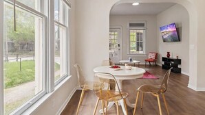 A dining area with a round table and chairs, large windows, and a view of the outdoors. - Pink on Delaware, Spacious 2BR Downtown Indy (Indianapolis)