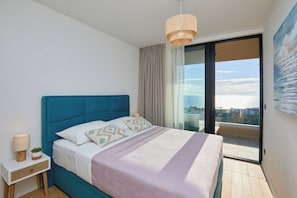 A modern bedroom with a large bed, a bedside table with a lamp, and a view of the city through a large window. - Hedera Estate, Hedera A44 (Dubrovnik)